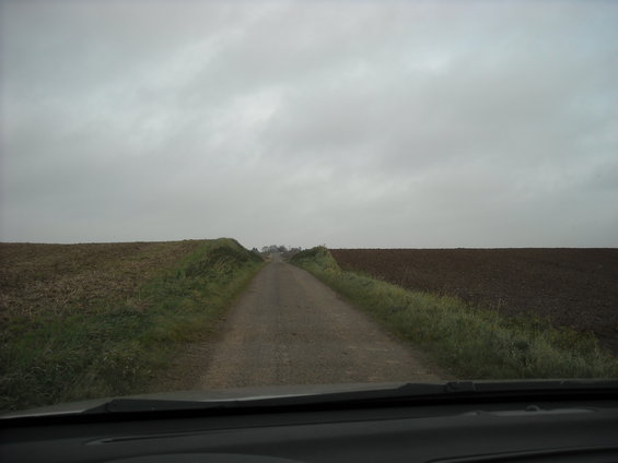 Dashboard view of a rural road under a cloudy sky