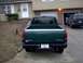 1995 GMC Sierra 1500 - Rear view of a green 1995 GMC Sierra 1500 pickup truck parked in a driveway, with a house and garage in the background.