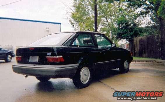 Black sedan parked outside, another car in background