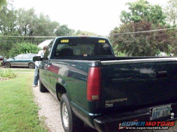 Pickup truck parked on gravel, another car in background. Person near driver's door