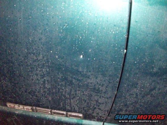 Teal truck door with water droplets and a chrome emblem reading 'SIERRA'