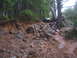 1989 Ford Bronco - Vehicle driving on a challenging, rocky, and muddy path in a wooded area.
