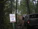 1989 Ford Bronco - Off-road vehicles navigate a trail in a wooded area, with a sign indicating trail information.