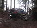 1989 Ford Bronco - A 1989 Ford Bronco navigates a challenging rocky path through a dense forest.