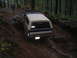 1989 Ford Bronco - Ford Bronco navigates a challenging, wet, and rocky off-road trail in a dense forest.