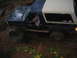 1989 Ford Bronco - This vehicle is navigating a challenging off-road course with large rocks and mud.