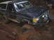 1989 Ford Bronco - A Ford Bronco navigates a challenging muddy terrain, with one wheel deep in the mire.