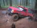 1989 Ford Bronco - This red SUV is navigating a challenging off-road course through a dense forest, demonstrating its capabilities.