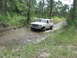 1989 Ford Bronco - White 1989 Ford Bronco navigates a water obstacle in a natural setting.
