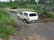 1989 Ford Bronco - A white Ford Bronco navigates a muddy water crossing in a wooded area.