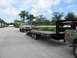 1989 Ford Bronco - A lifted 1989 Ford Bronco is parked next to a flatbed trailer.