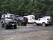 1979 Ford Bronco - Multiple Ford Broncos and RVs gathered in a muddy, wooded area.