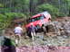 1979 Ford Bronco - A red SUV with a snorkel attachment navigates a challenging rocky trail with two people nearby.