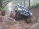 1979 Ford Bronco - This modified SUV tackles a challenging muddy off-road course, with a club sticker visible on its windshield.