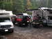 1979 Ford Bronco - Multiple vehicles, including campers and off-road SUVs, are parked together in a wooded campsite.