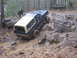 1979 Ford Bronco - Two Ford Broncos tackle a challenging muddy and rocky off-road course in a wooded area.
