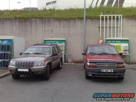 Jeep Grand Cherokee and red minivan parked at air and water station