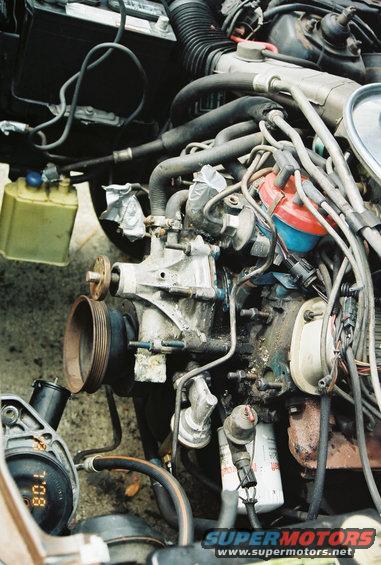 Engine bay with hoses, wires, distributor, oil filter, and a gauge showing 80.1