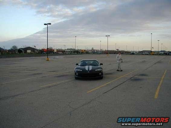 Black Dodge Viper with white stripes parked in an empty lot, person standing nearby