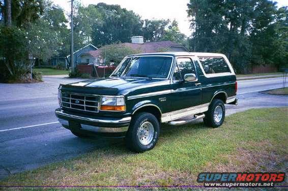Dark green 1992 Ford Bronco parked on grass next to a road, front 3/4 view