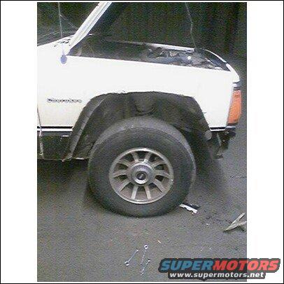 White SUV with hood open, showing front fender and wheel. Some tools are on the ground