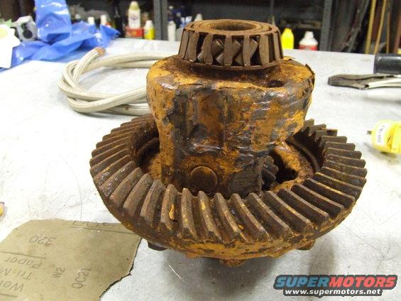 Rusty differential gear assembly with a bearing on top, on a workbench with sandpaper
