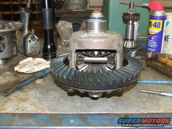 Differential gear assembly with ring and pinion gears on a workbench with tools and spray cans