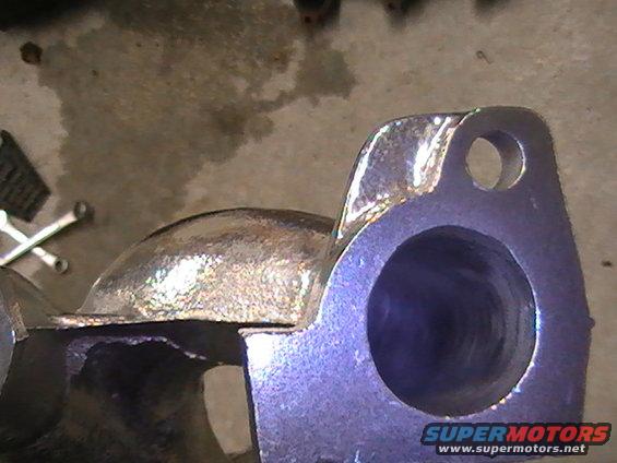 Close-up of a metal exhaust manifold part with two bolt holes