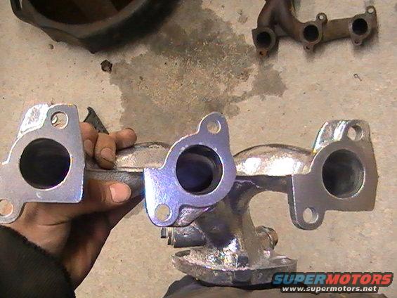 exhaust manifold held in hand, another exhaust manifold on the ground