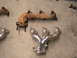 1990 Ford Probe - Two exhaust manifolds, one old and rusty, the other polished and new, lie on a concrete surface.