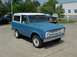 1966 Ford Bronco - A blue 1966 Ford Bronco with a white roof is parked on a concrete surface, with another vehicle visible behind it.
