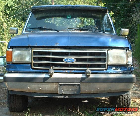 Blue 1990 Ford Bronco front view, dented bumper, chrome grille with Ford logo