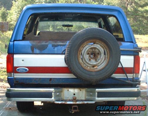 Rear view of a blue and red striped 1990 Ford Bronco with a spare tire on the back