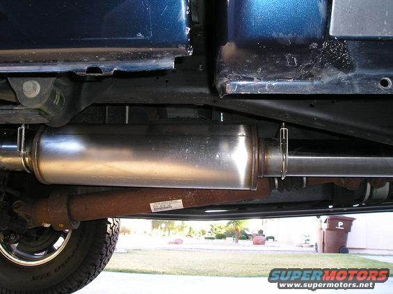 Underside view of a truck's exhaust system, showing the muffler and driveshaft