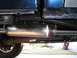 2001 Ford F-350 - Close-up of a truck's exhaust system, including the muffler and driveshaft, with a trash can visible in the background.