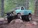 1992 Ford Ranger - A teal pickup truck navigates a rocky, muddy trail in a wooded area.