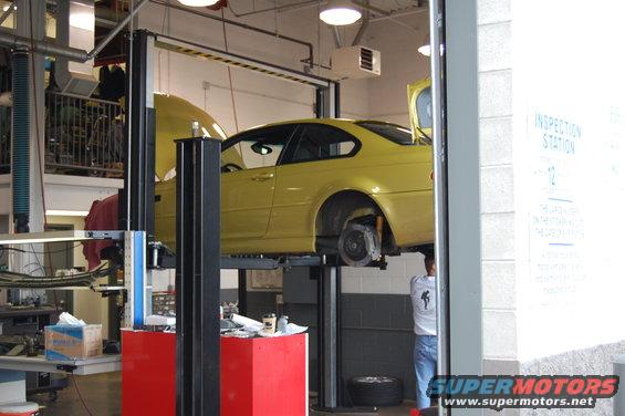 Yellow 2002 BMW M3 coupe on a lift, front wheel removed