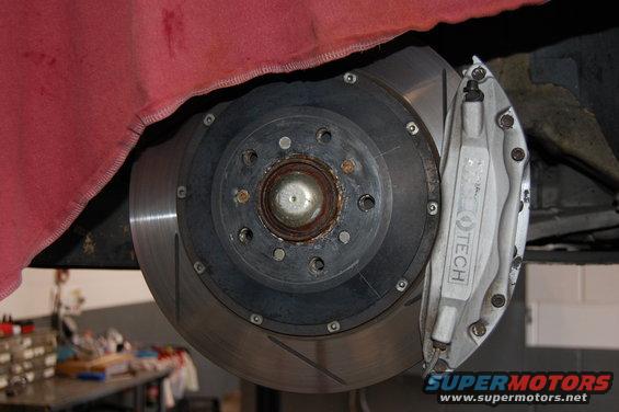 Close-up of a car's front brake rotor and caliper with 'TECH' visible on the caliper