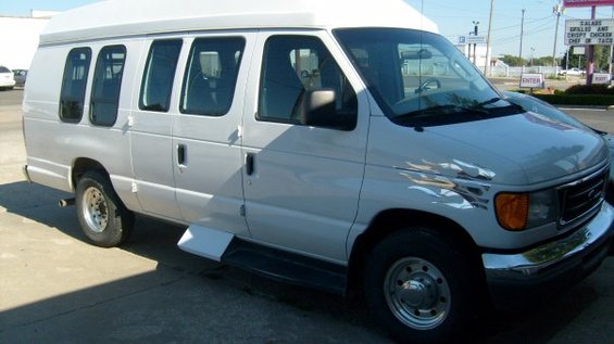 White 2006 Ford E250 van with flame decals on the fender, seen from the front 3/4 angle