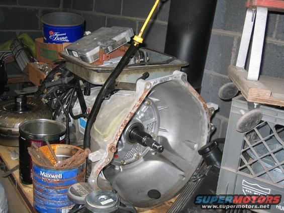Transmission bell housing and torque converter on a workbench with various parts and containers