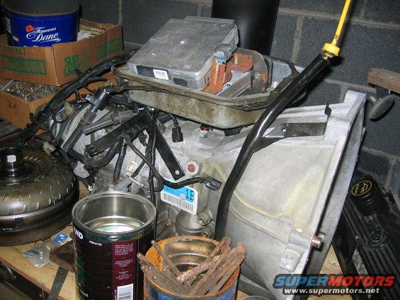 Engine transmission assembly with torque converter and various engine components. A yellow dipstick handle is visible