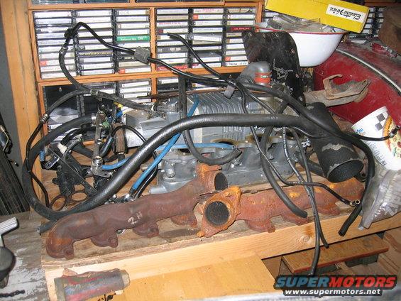 Engine part with exhaust manifold and supercharger