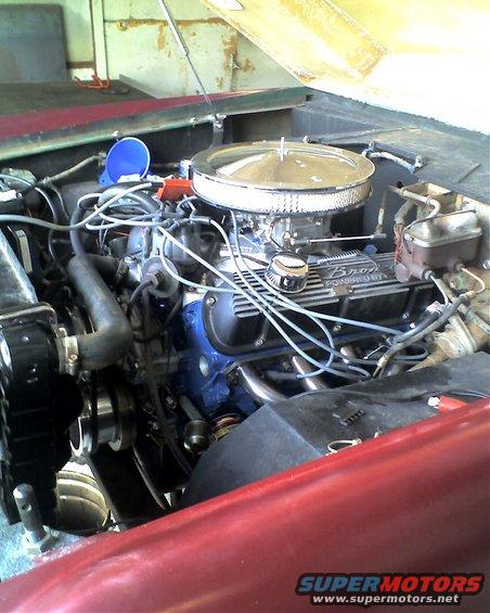 Engine bay of a red vehicle, showing the V8 engine with a chrome air cleaner and "Bronco" valve covers