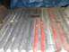 1988 Ford Bronco - Corroded metal floor with red stripes, possibly from a vehicle's cargo area.