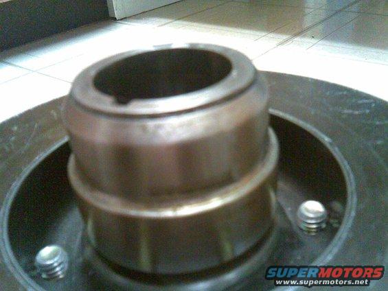 Close-up of a metal part with three visible bolts and a cylindrical protrusion