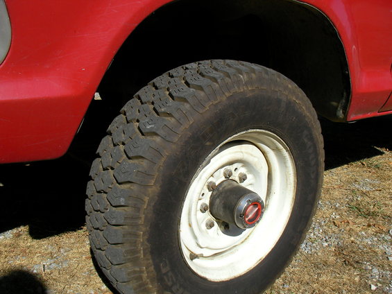 Close-up of a red truck's front wheel with a white rim and a black tire