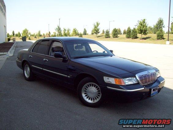 Dark sedan parked on asphalt, facing right. Chrome grille, headlights visible