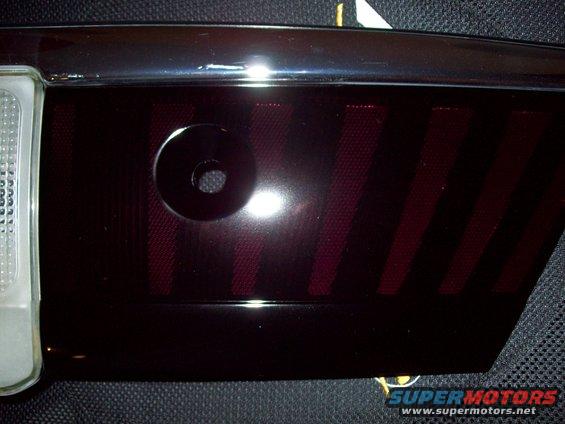 Close-up of a dark, tinted car tail light with red stripes inside