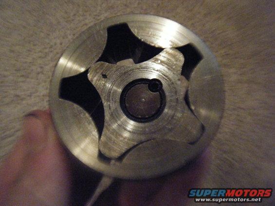 Close-up of a metal oil pump rotor with six lobes, held by a hand
