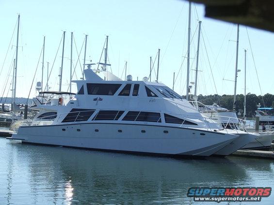 Large white yacht docked next to sailboats